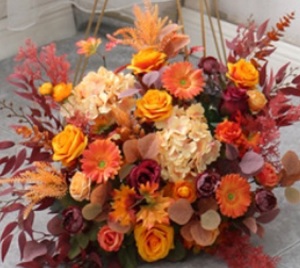 Orange roses gerberas carnations with golden cane palm leaves tropical foliage in basket arrangement